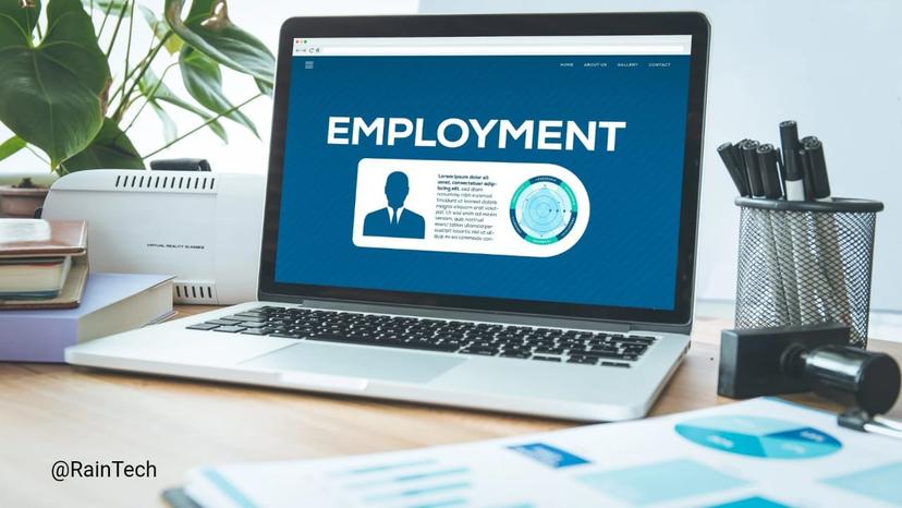 A Laptop on a desk displaying an employment webpage with charts, surrounded by office supplies and plants.