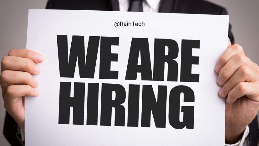 A professional holding a 'We Are Hiring' sign for RainTech, representing a remote .NET Backend Engineer job opportunity.