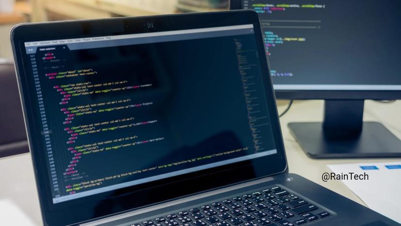A laptop and a second monitor displaying lines of backend code in a dark mode text editor, representing the tech stack for Indonesian engineers.